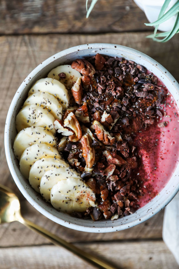 A 5-minute nutritious smoothie bowl with frozen raspberries and bananas. Topped with fruit, nuts and seeds for a healthy snack.