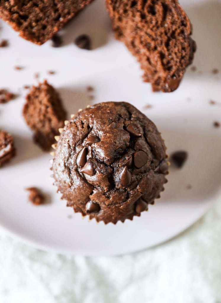 Top down view of some chocolate oat muffins on a pink plate with a linen. 