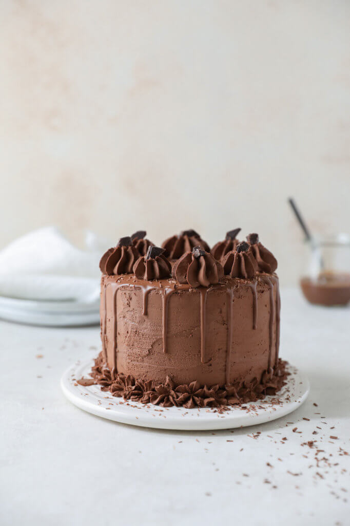 A straight on view of a chocolate cake with chocolate frosting with chocolate shavings