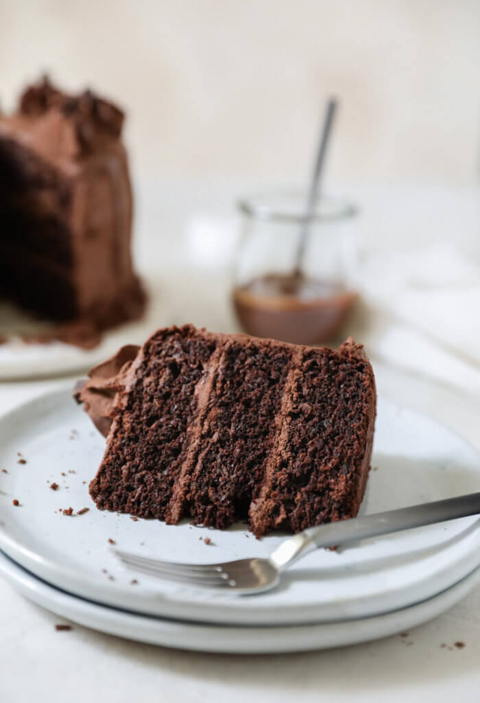 A piece of chocolate cake on a plate with a fork. 