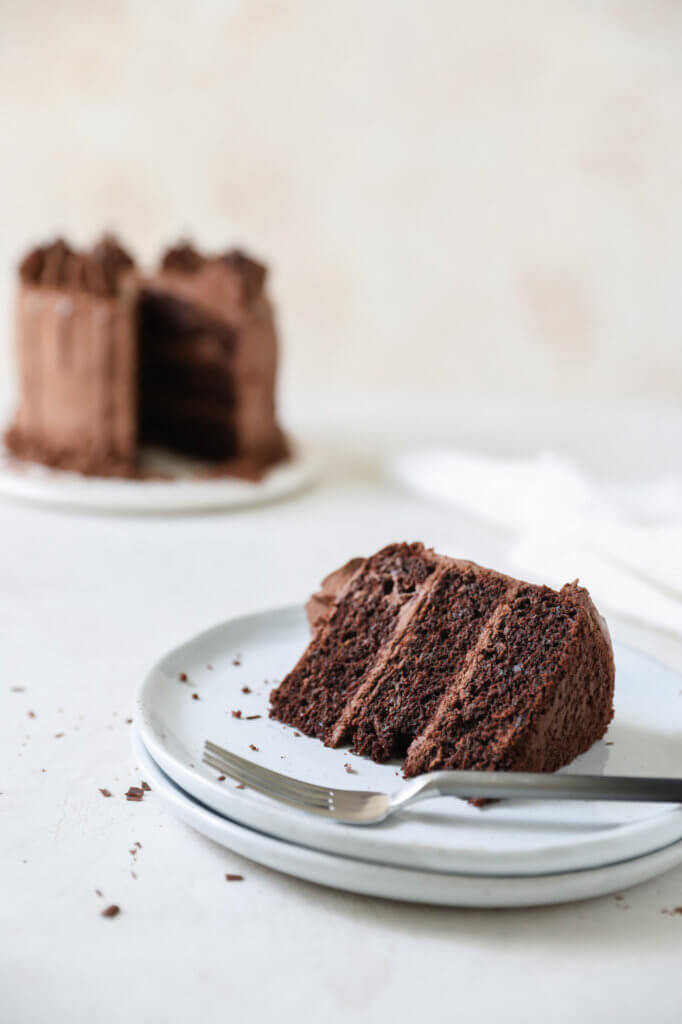 Piece of chocolate zucchini cake on a plate with a fork. 