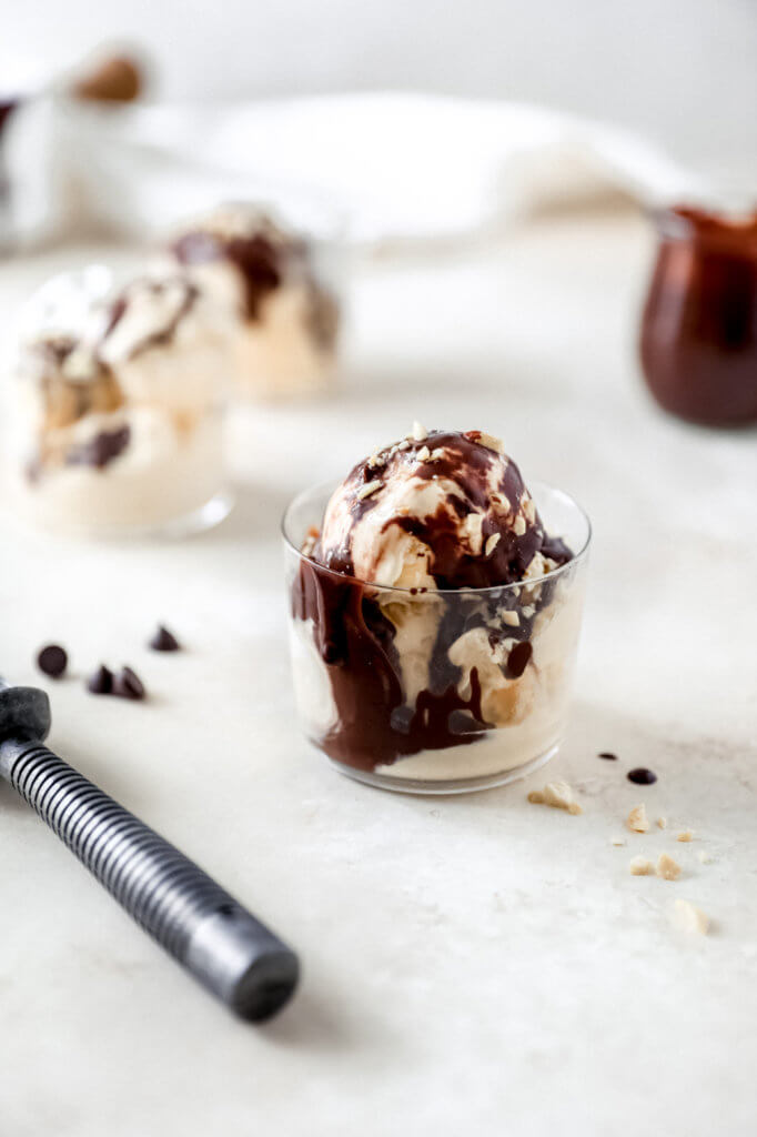 A small glass with melting vanilla ice cream and hot fudge. 
