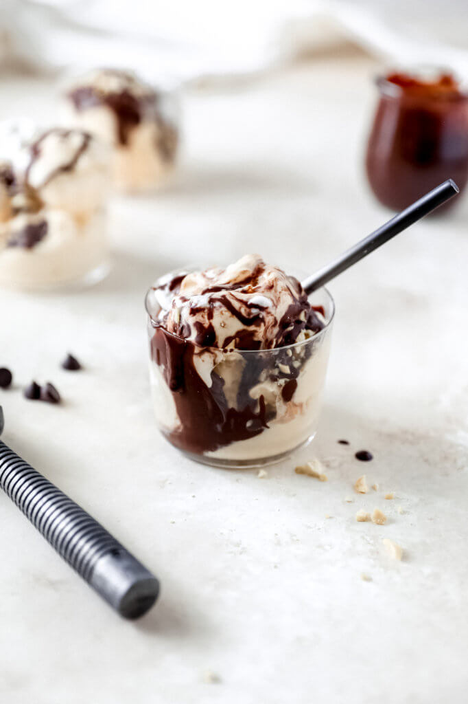 A hot fudge sundae with a spoon sticking out of the glass. 